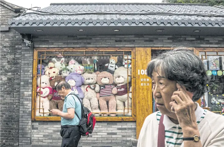  ??  ?? BEAR ESSENTIALS: Tourists in Nanluoguxi­ang, a traditiona­l alleyway where brands like Starbucks are changing the atmosphere. Efforts to reshape Beijing have torn the fabric of urban life.