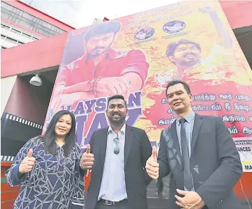  ??  ?? Karthikgeh­yen (centre), Tang (right) and Vijay fan Lily Tiong, give their thumbs-up in front of a giant poster of Vijay at King’s Trioplex.