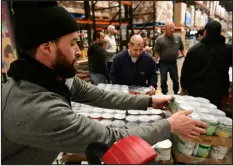  ?? HELEN H. RICHARDSON — THE DENVER POST ?? Nicholas Paradisi, left, a distributi­on specialist, works with volunteers to organize pallets of canned goods for orders at the Food Bank of The Rockies on Tuesday.