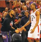  ?? Gregory Shamus Getty Images ?? DRAKE greets the Raptors’ Kawhi Leonard at Tuesday’s playoff game. Some don’t like the rapper’s act.