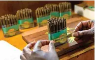  ??  ?? A woman places a branded label on a pack of cigars at the Mosi Oa Tunya, the first cigar manufactur­ing plant in Zimbabwe.