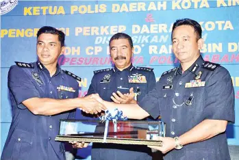  ??  ?? Ramli (centre) witnesses outgoing KK police chief Chandra (left) handing over his duties to successor Habibi yesterday.