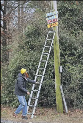  ??  ?? Kyle uses a telescopin­g ladder to install some newly created street art on a roadside pole.