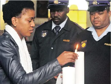  ?? PICTURE: BHEKI RADEBE ?? IN REMEMBRANC­E: Constable Noludwe Tshanga lights a candle during the memorial service of her boyfriend, Constable Mthetho Sandla, who shot and killed in Delft.
