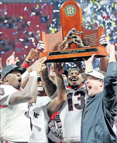  ?? [JOHN BAZEMORE/THE ASSOCIATED PRESS] ?? Georgia coach Kirby Smart gets help from some of his players in hoisting the SEC championsh­ip trophy after defeating Auburn.