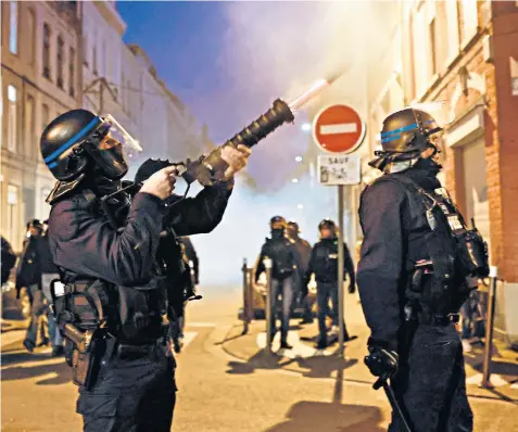  ?? ?? A police officer fires a tear gas canister launcher during a protest in Lille in northern France after the government pushed a pension reform through parliament without a vote