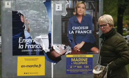  ?? BOB EDME, THE ASSOCIATED PRESS ?? A woman walks past electoral posters of French presidenti­al candidates Emmanuel Macron, torn at left, and Marine Le Pen in Ascain on Tuesday.