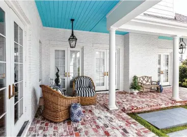  ?? Julie Soefer ?? Wicker chairs with striped cushions are situated in a corner of the patio that features a walkway made of reclaimed red brick at The Woodlands home of Paige and Matt Hammit.