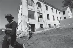  ?? GENARO MOLINA/LOS ANGELES TIMES ?? Constructi­on workers walk past a building that is being refurbishe­d as housing for veterans on the Veterans Affairs West L.A. campus.