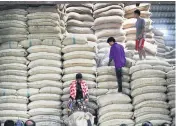  ?? TAWATCHAI KEMGUMNERD ?? Workers unload sacks of rice at a warehouse. Rice export prospects remain dim as a result of the stronger baht.