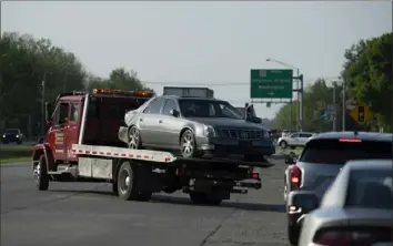  ?? Denny Simmons / Evansville Courier & Press ?? A tow truck hauls away the Cadillac sedan that fugitives Casey White and Vicky White were driving when law enforcemen­t officials forced them into a ditch at Burch Drive in Evansville, Ind., after a short chase Monday.