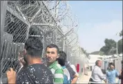  ??  ?? Migrants and refugees wait outside the European Asylum Support Service offices inside the Moria camp.