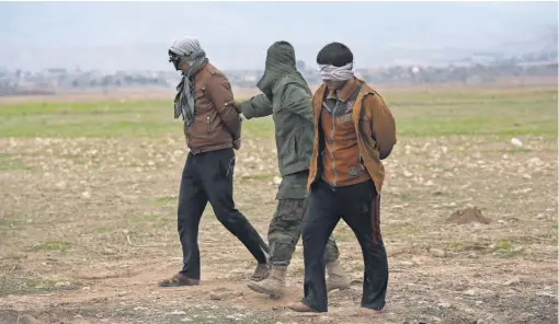  ?? JOHN MOORE, GETTY IMAGES ?? Two captured, blindfolde­d Islamic State fighters are escorted near Sinjar, Iraq, which was seized by Kurd forces two weeks ago.