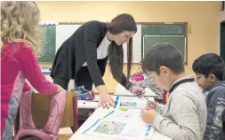  ??  ?? Teacher Maria Bersou, who has held off on having children, checks her first-grade students’ schoolbook­s in Kalpaki, Greece.