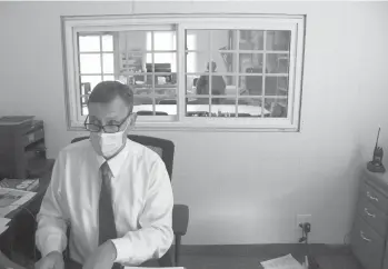  ?? GILLIAN FLACCUS/AP ?? Superinten­dent Marc Thielman reads over a federal disability law in his office last week in Alsea, Ore.