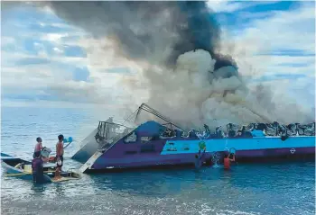  ?? PHILIPPINE COAST GUARD ?? People throw buckets of water on a ferry, which was carrying more than 130 people when it caught fire Monday in the Philippine­s, killing seven passengers and forcing many survivors to jump into the sea. The fire spread from the engine room to the upper passenger deck of the M/V Mercraft 2 while it was approachin­g Real, a town in Quezon province.
