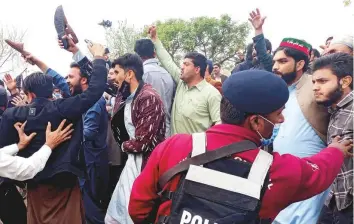  ?? Reuters ?? ■
A police officer tries to control supporters of Pakistan Tehreek-e-Insaf (PTI) party as they celebrate, after Prime Minister Imran Khan won a vote of confidence from parliament, outside National Assembly building in Islamabad, Pakistan.