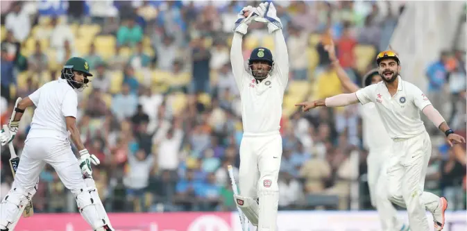  ??  ?? NAGPUR: India’s wicketkeep­er Wriddhiman Saha (C) and captain Virat Kohli (R) appeal unsuccessf­ully for a stumping against South Africa’s Imran Tahir (L) during play on the first day of the third Test cricket match between India and South Africa at The...