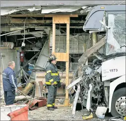  ??  ?? WRECKED: A firefighte­r surveys the smashed front end of the charter bus in Flushing Monday after it hit a city bus and plowed into an eatery.