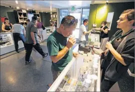  ?? Brennan Linsley
Associated Press ?? CUSTOMERS shop for marijuana in Denver. Because U.S. law forbids banks from working with cannabis sellers, the industry runs almost entirely on cash.