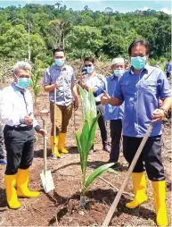  ??  ?? Dr Abdul Rahman (right) during a photo call after planting a coconut sapling at Kampung Sayung.