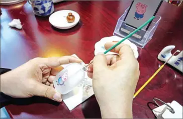  ?? AFP ?? Chinese artist Wei Dongfang draws a Peppa Pig figure inside a snuff bottle at his workshop in Beijing.