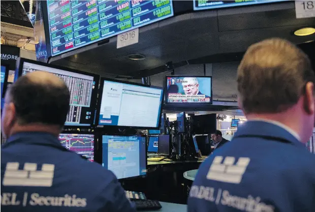  ?? BRYAN R. SMITH / AFP / GETTY IMAGES ?? News of Attorney General Jeff Sessions’ departure is shown on screens as traders work on the floor at the New York Stock Exchange.