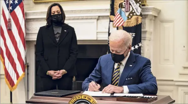  ?? Anna Moneymaker / New York Times ?? President Joe Biden signs executive orders Friday at the White House as Vice President Kamala Harris looks on. Biden signed executive orders aimed at steering additional federal aid to families struggling to afford food amid the coronaviru­s pandemic and at helping workers stay safe on the job.