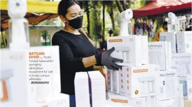  ??  ?? BATTLING COVID ... Trader Yuliana Sabaruddin arranging sanitisati­on equipment for sale in Kuala Lumpur yesterday. – BERNAMAPIX