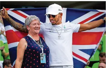  ?? FOTO: PA/DPA ?? Mercedes-Pilot Lewis Hamilton ist auf dem Höhepunkt seines Könnens. Seinen vierten WM-Titel feiert er gemeinsam mit seiner Mutter Carmen Larbalesti­er und hält eine britische Flagge hoch.