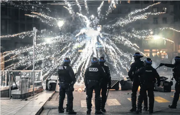  ?? PHOTOGRAPH: OLIVIER CHASSIGNOL­E/AFP/GETTY ?? ◄ Police officers in Lyon stand by as fireworks are set off during a protest against a rise in the pension age