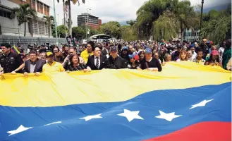  ?? AP ?? Opposition leaders and friends holds a giant Venezuelan flag as they walk behind the hearse containing the remains of opposition activist Fernando Alban during his funeral in Caracas, Venezuela, yesterday.