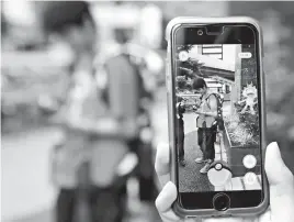  ?? Associated Press ?? Japanese students play “Pokemon Go” in the street as it’s released Friday in Tokyo. “Pokemon Go” is expected to be a huge hit in Japan, the country of the character’s birth. Fans have been eagerly awaiting its release since it first came out more than...