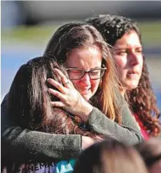  ?? AP ?? Top left: Students are released from a lockdown outside Stoneman Douglas High School in Parkland after the campus shooting. Bottom left: Medical personnel tend to a victim outside the school. Above: Survivors console one another after the deadly rampage.
