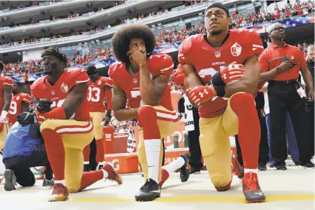  ?? Thearon W. Henderson / Getty Images 2016 ?? Eli Harold (left), Colin Kaepernick and Eric Reid take a knee during the national anthem before a 2016 game to protest police violence against African Americans, part of a protest that continues this season despite having cost Kaepernick his NFL career.