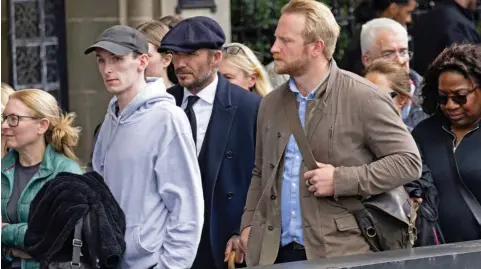  ?? ?? Incognito: Beckham wears a cap and suit as he waits with other mourners, having joined the queue at 2am