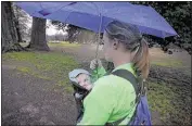  ?? MARK WEBER COMMERCIAL APPEAL ?? As the heavy raindrops tap the blue umbrella, a dry and happy 5-month-old Josie Michalsky takes in the sights of Overton Park while her mother Briahna Michalsky walks.