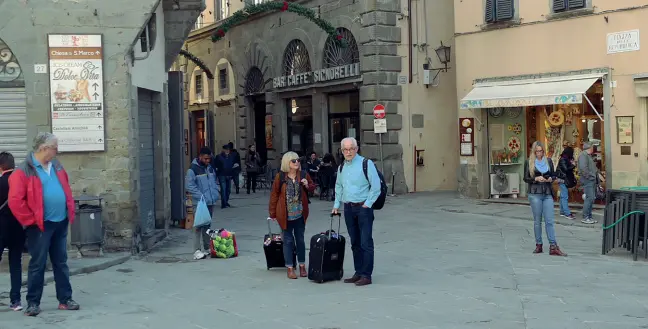  ??  ?? Due turisti appena sbarcati ieri in piazza della Repubblica a Cortona, in attesa del proprietar­io dell’appartamen­to turistico affittato online