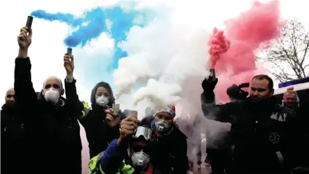  ?? | Reuters ?? FRENCH ambulance drivers hold blue, white and red smoke canisters during a demonstrat­ion at the Place de la Concorde in Paris yesterday. French Prime Minister Edouard Philippe met opposition leaders yesterday as President Emmanuel Macron sought a way to defuse nationwide protests over high living costs. The “yellow vest” revolt’s members come principall­y from the hard-pressed middle class and blue-collar workers living outside the big cities, but it also has more radical fringe elements.