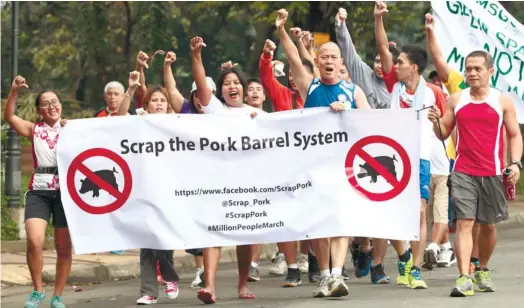  ?? (AP FOTO) ?? NO MORE ‘PORK’ PLEASE. Roman Catholic priest Fr. Robert Reyes (third from right) flashes a thumb-down sign with other protesters as they hold a slogan during a protest run to call for the scrapping of a corruption-tainted Priority Developmen­t...