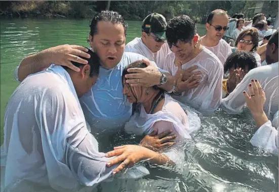  ?? DAVID SILVERMAN / GETTY ?? Un grupo de brasileños evangélico­s durante una ceremonia de bautismo multitudin­ario