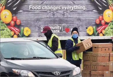  ?? Associated Press photos ?? Volunteers load boxes of food into a car during a Greater Pittsburgh Community Foodbank drive-up food distributi­on in Duquesne, Pa., on Nov. 23. Americans who struggled through 2020 could face more hardship in the year ahead as pandemic related payments and protection­s come to an end.