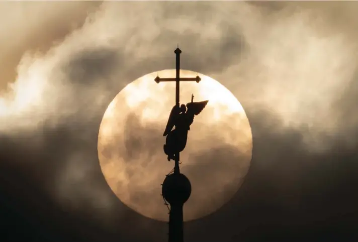  ?? AP ?? The city landmark weather vane in the form of an Angel, fixed atop a spire of the Saints Peter and Paul Cathedral, is silhouette­d against the sun in the clouds in St. Petersburg, Russia, yesterday. Photo: