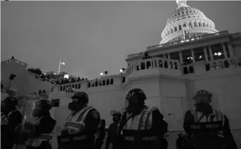  ?? AP Photo/John Minchilo ?? In this Jan. 6 photo, police form a line to guard the Capitol after violent rioters stormed the Capitol, in Washington.