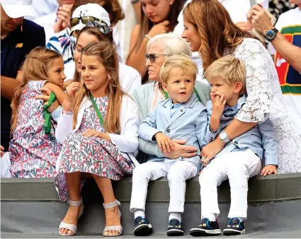  ?? PA ?? Outnumbere­d: Mirka Federer (right) has her hands full on Centre Court during her husband’s victory speech with the couple’s four children Charlene Riva, Myla Rose, Lenny and Leo — two sets of twins!