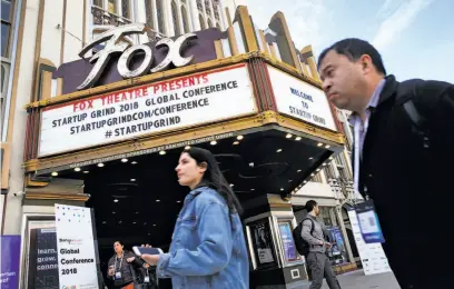  ?? Paul Chinn / The Chronicle ?? Attendees walk past the Fox Theatre on Broadway in Redwood City during the Startup Grind Global Conference.