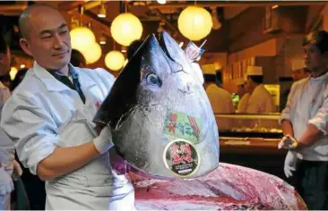  ??  ?? bluefin tuna being cut at a sushi restaurant outside Tsukiji fish market in Tokyo, Japan. environmen­talists are calling for stronger measures to stamp out illegal fishing of tunas.