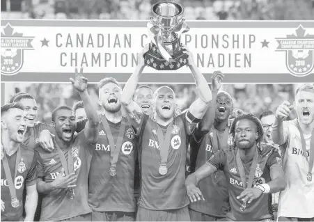  ?? CHRIS YOUNG, THE CANADIAN PRESS ?? Toronto FC captain Michael Bradley hoists the Voyageurs Cup after beating the Whitecaps 5-2 on Wednesday.