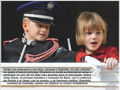  ?? ?? Arriba, los soberanos y sus hijos, Jacques y Gabriella, de rojo, saludando desde el balcón principal. Charlene no ocultó su felicidad al volver a participar en uno de los días más grandes para el principado. Sobre estas líneas, el príncipe heredero y marqués de Baux, con el uniforme de Policía y el «kepi» con la corona, y su hermana melliza, Gabriella,
condesa de Carladés, camino de celebrar su octavo cumpleaños