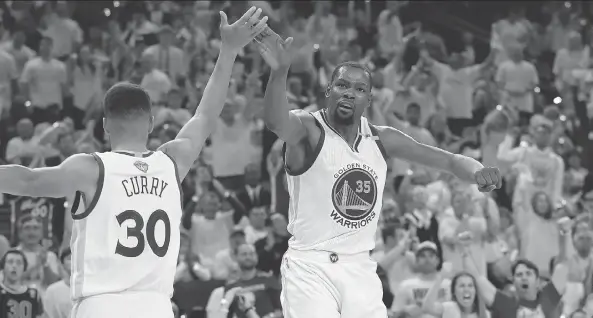  ?? EZRA SHAW/GETTY IMAGES ?? Golden State Warriors Stephen Curry and Kevin Durant high-five after a play in Game 2 of the NBA Finals on Sunday in Oakland, Calif. In their first two playoff games against the Cleveland Cavaliers, Durant averaged 35.5 points and 11 rebounds, and...